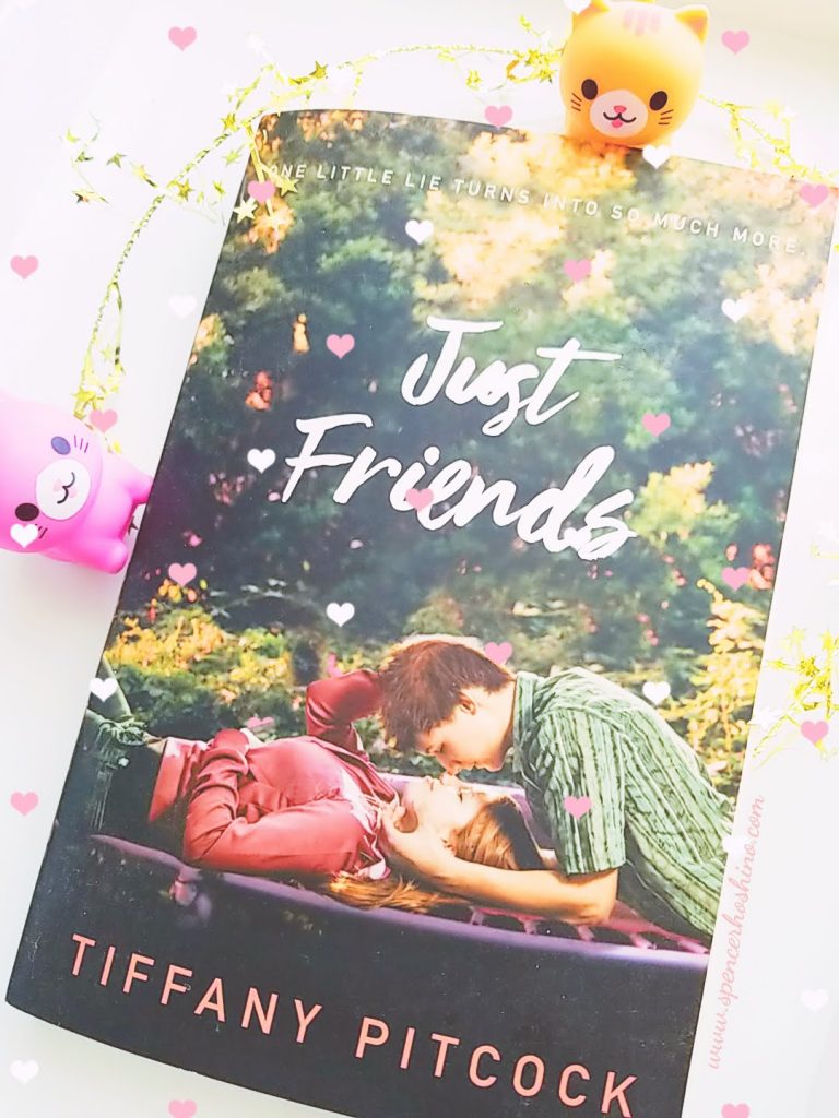 Cover for the book Just Friends by Tiffany Pitcock. Cover features a girl in a red jacket laying down with a boy in a green shirt leaning over her. 